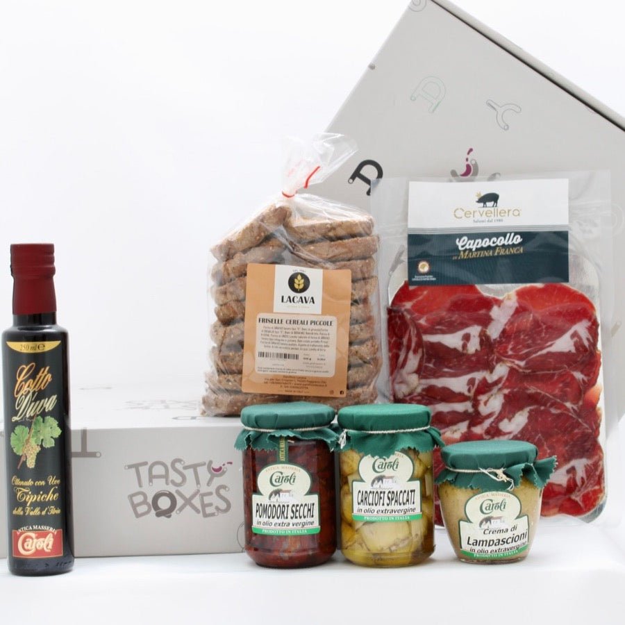 Box aperitivo TastyBoxes contenente friselline piccole ai cereali, pomodori secchi, carciofi spaccati, crema di lampascioni, capocollo a fette sottovuoto, cotto d'uva 